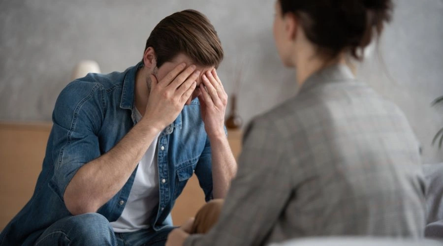 Man with hands over his face with physician looking on - Health care service