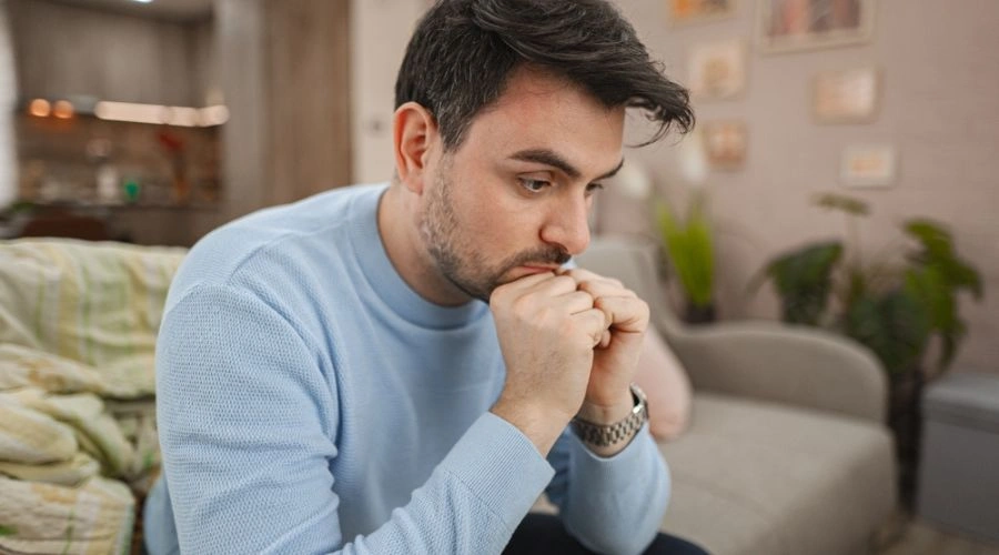 Man sitting with fists in front of his mouth being Emotionally Numb
