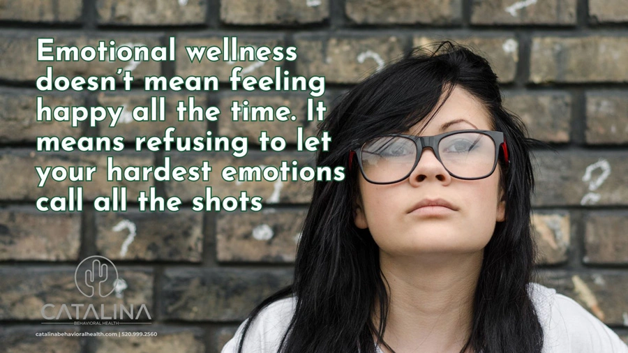Female with glasses standing in front of brick wall - Emotions Anonymous - Catalina Behavioral Health