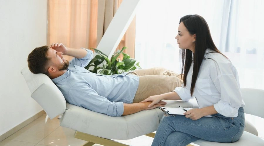 Male patient on a chaise with anguish on his face talking to counselor consoling him - Mental Health Professionals at Catalina