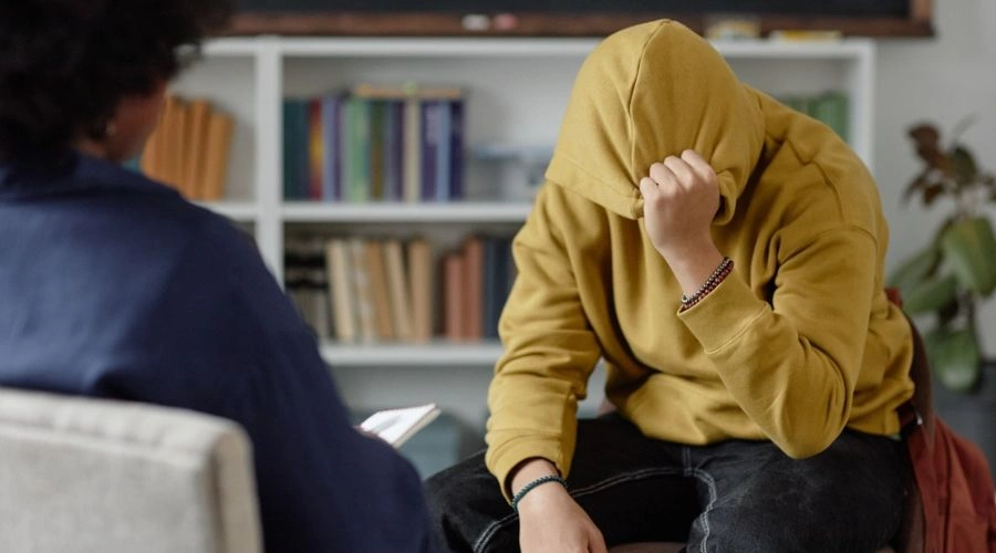 Image of a man with hoodie pulled over his face talking to counselor in Trauma-Informed Treatment