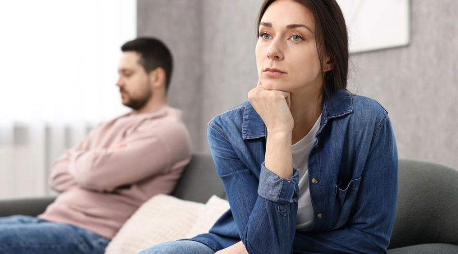 Image of a unhappy couple ignoring each other as both sit away from each other on a sofa