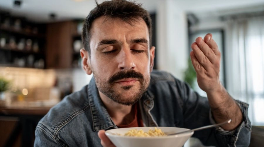 Man enjoying the sensory experience of smelling pasta is  part of the grounding techniques